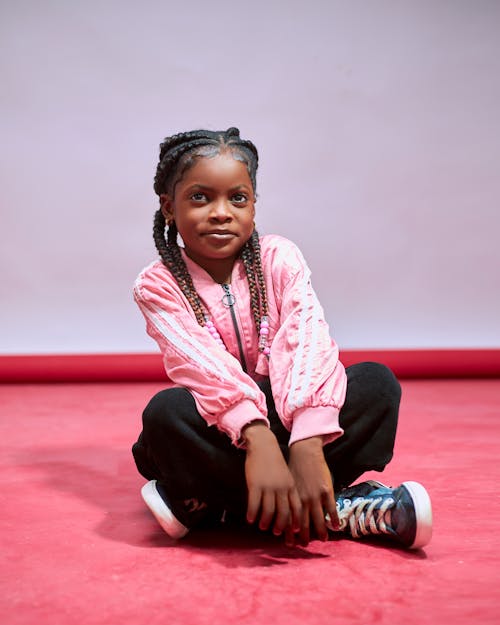 A young girl sitting on the floor in pink