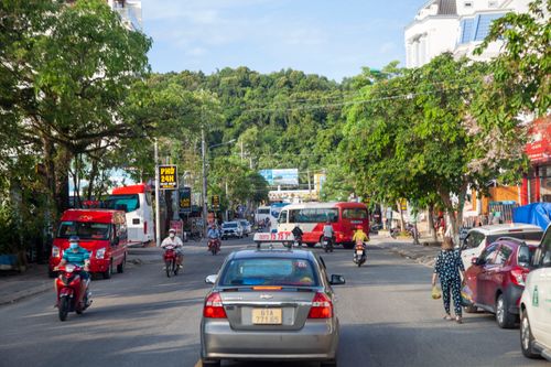 Free A vibrant street scene with cars, buses, and motorcycles on a sunny day. Stock Photo