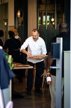 Chef presenting dishes to customers in a lively restaurant setting, showcasing hospitality.