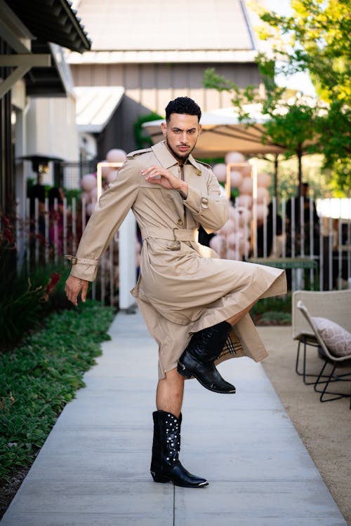 A man in a trench coat and boots is dancing