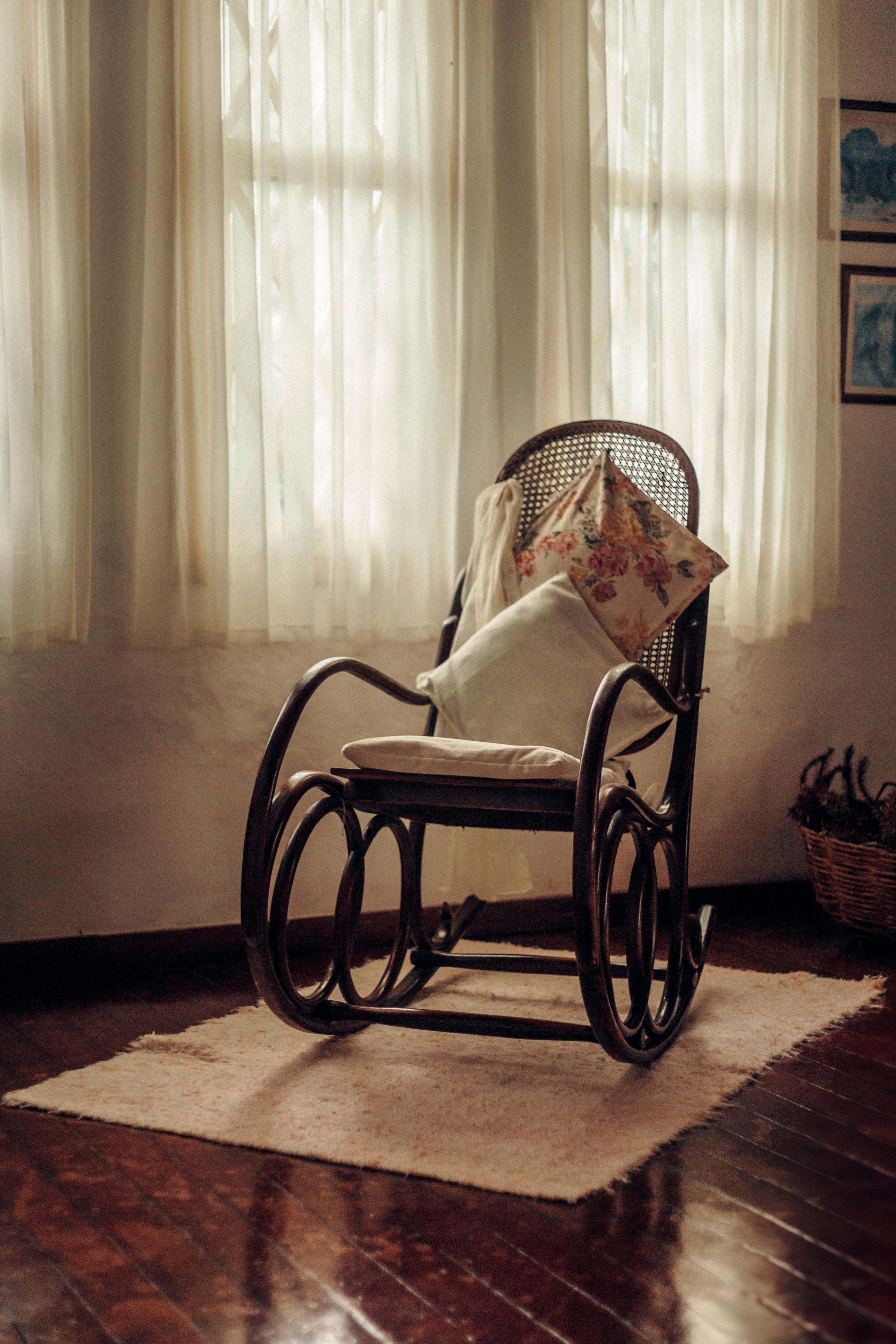 Warm vintage-style room with a wooden rocking chair, cushion, and soft lighting.
