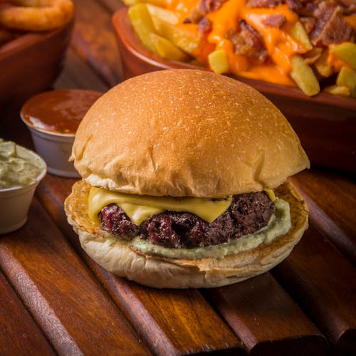 A burger with fries and dip on a wooden table