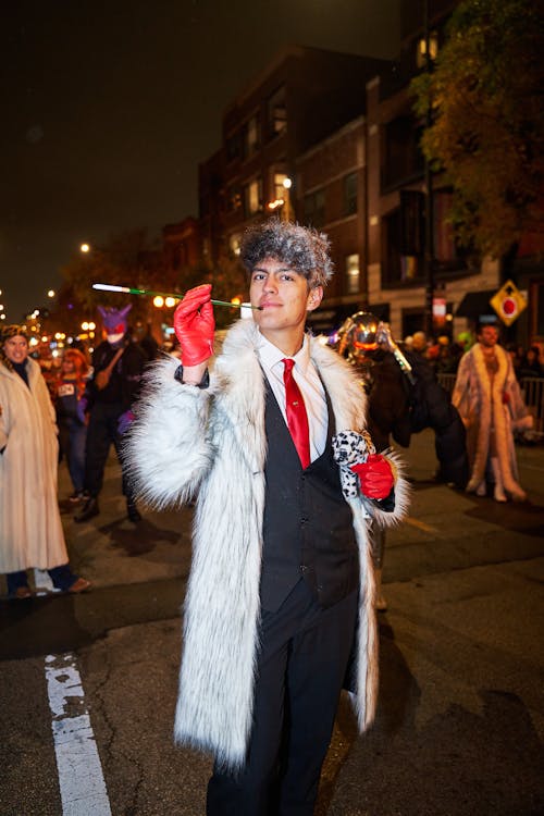 A man in a fur coat and red gloves is walking down the street