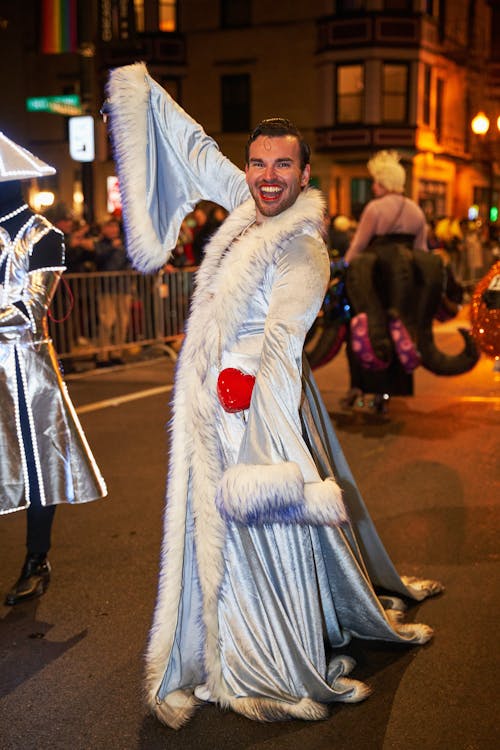 A man in a white fur coat and cape is dancing