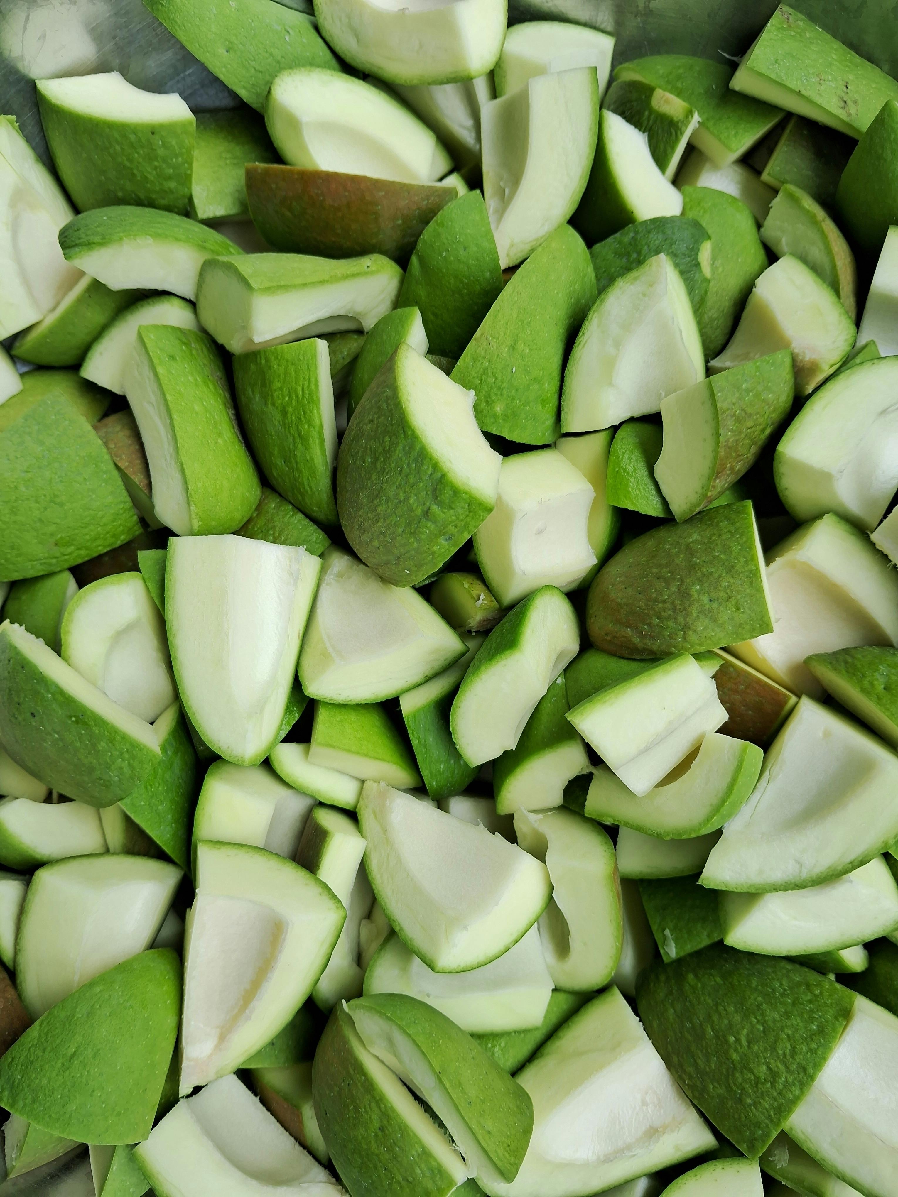 Vibrant and freshly cut green mango pieces in a pile, showcasing texture and freshness.