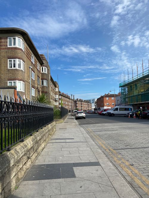Free A scenic view of a residential street in Dublin, showcasing historic brick townhouses under a vibrant blue sky. Stock Photo