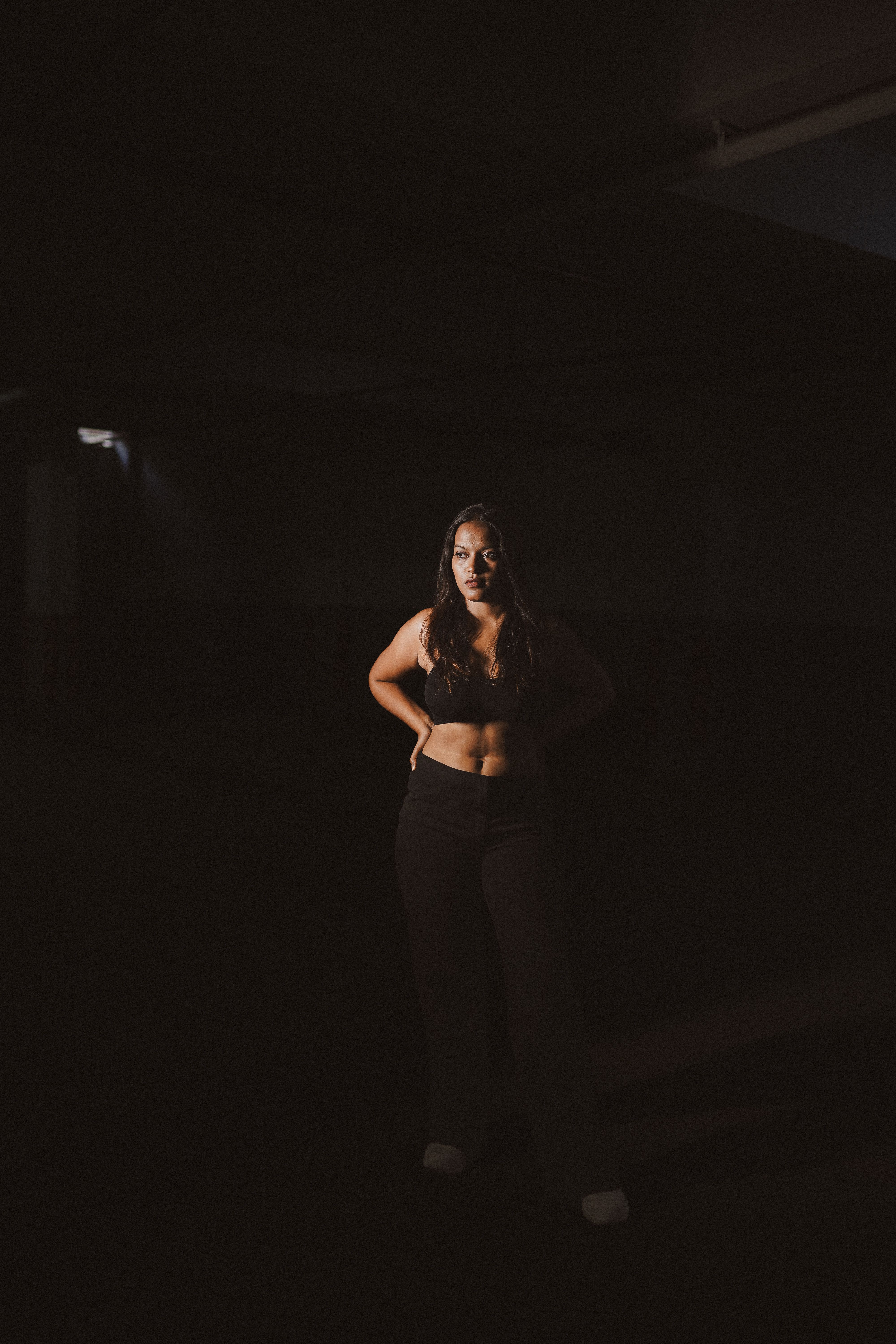 A Young Woman Standing in a Dark Room · Free Stock Photo