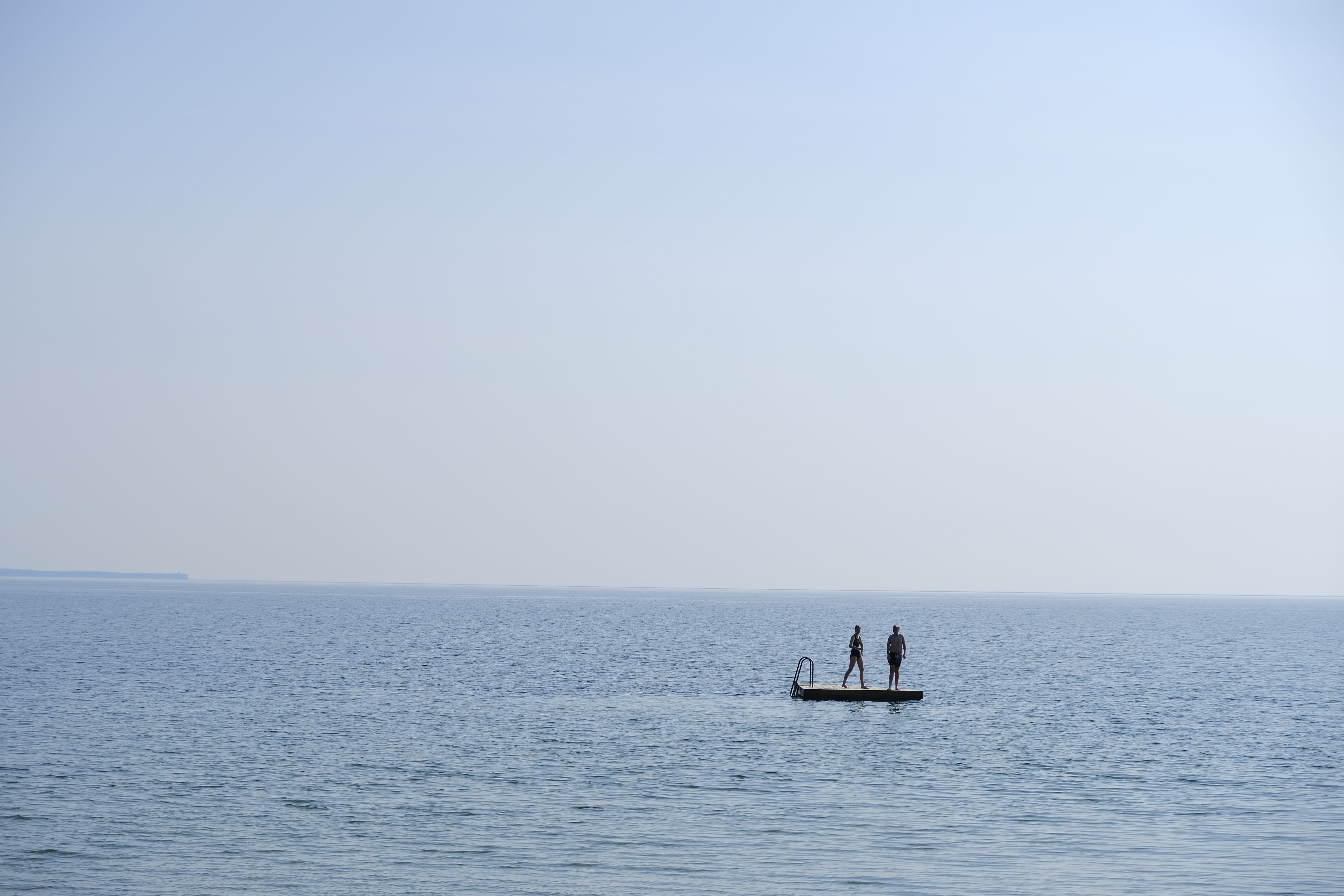 Peaceful image of two individuals standing on a raft in the calm waters of Gotland, Sweden.