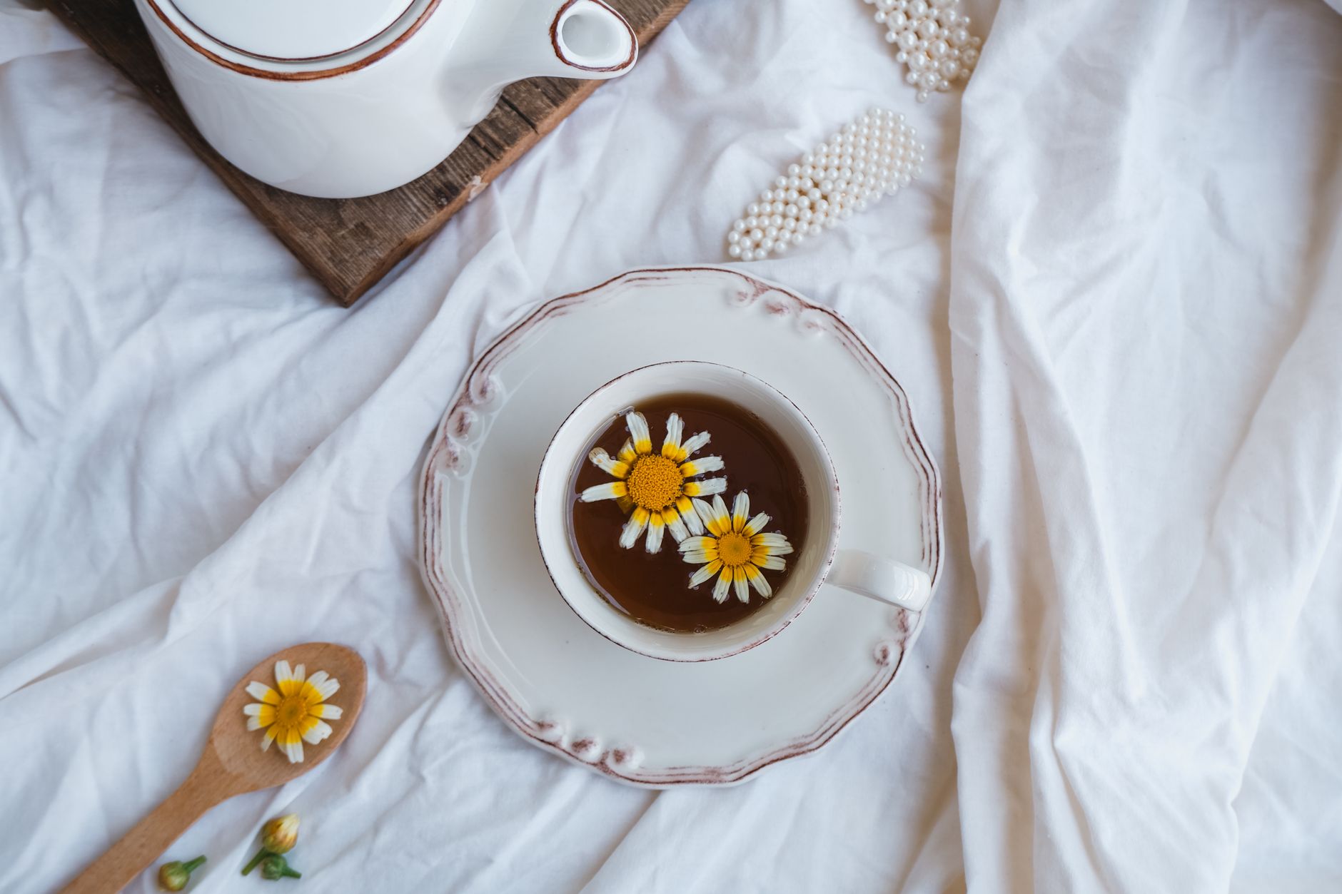 Enjoy a tranquil moment with chamomile tea, daisies, and rustic charm in a cozy setting.