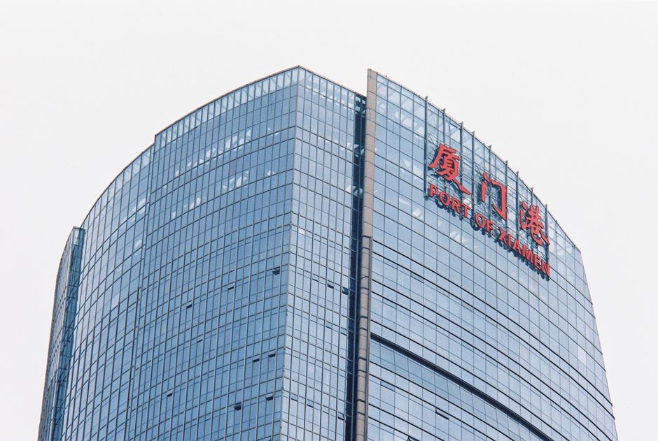 Contemporary glass skyscraper in Xiamen displaying the Port of Xiamen signage.