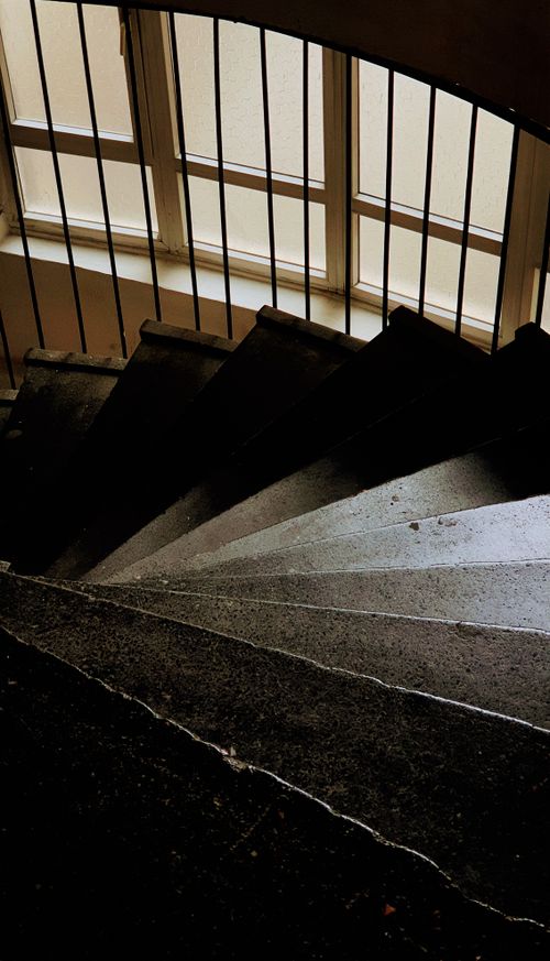 Free A dramatic view of a curved staircase beside large windows casting light. Stock Photo