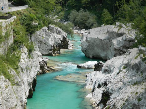 Experience the vibrant turquoise waters of the Soča River amid majestic rocks and lush greenery in Tolmin, Slovenia.
