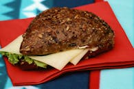 A sandwich with cheese and lettuce on a red napkin