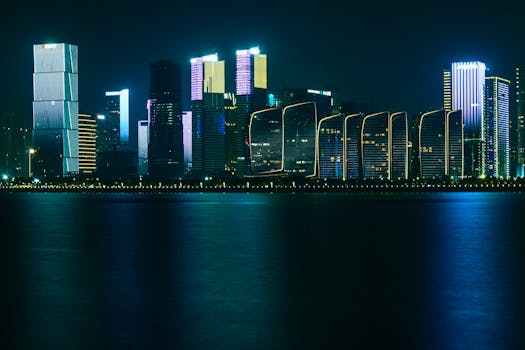 Modern skyscrapers glowing at night, reflected in the waterfront's serene water.