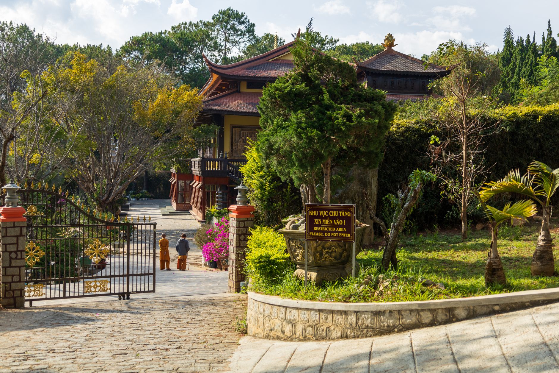 Truc Lam Buddhist Monastery gate surrounded by lush greenery in Da Lat, Vietnam on a sunny day.
