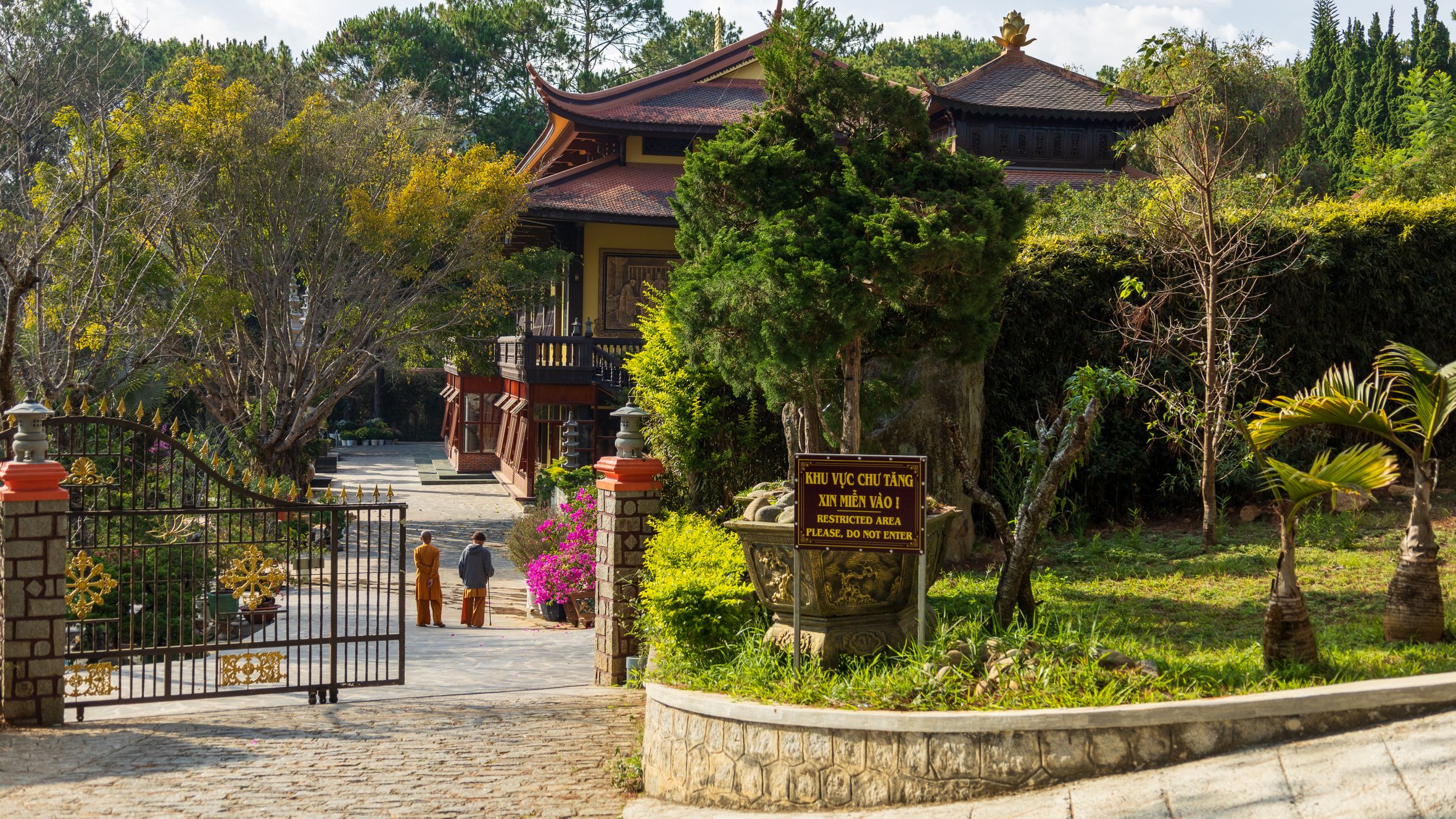 Truc Lam Buddhist Monastery gate surrounded by lush greenery in Da Lat, Vietnam on a sunny day.