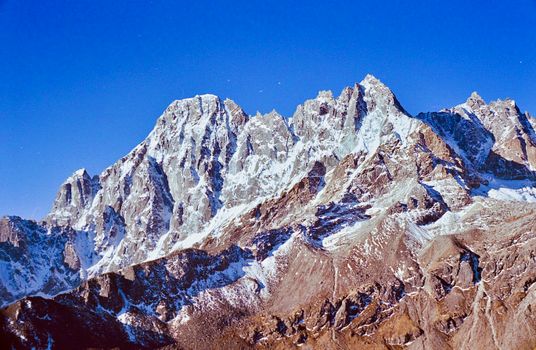Breathtaking view of a snow-covered mountain range under a vibrant blue sky, perfect for nature enthusiasts.