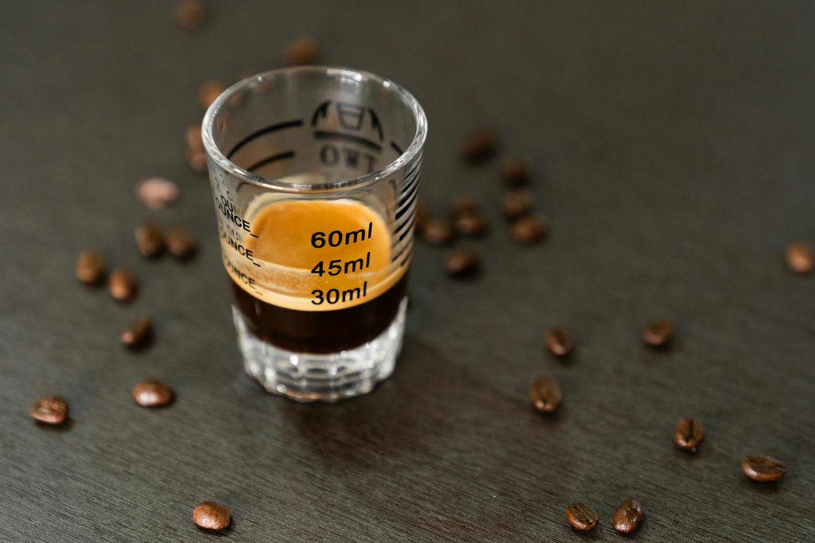 Espresso shot with crema in a measuring glass and coffee beans