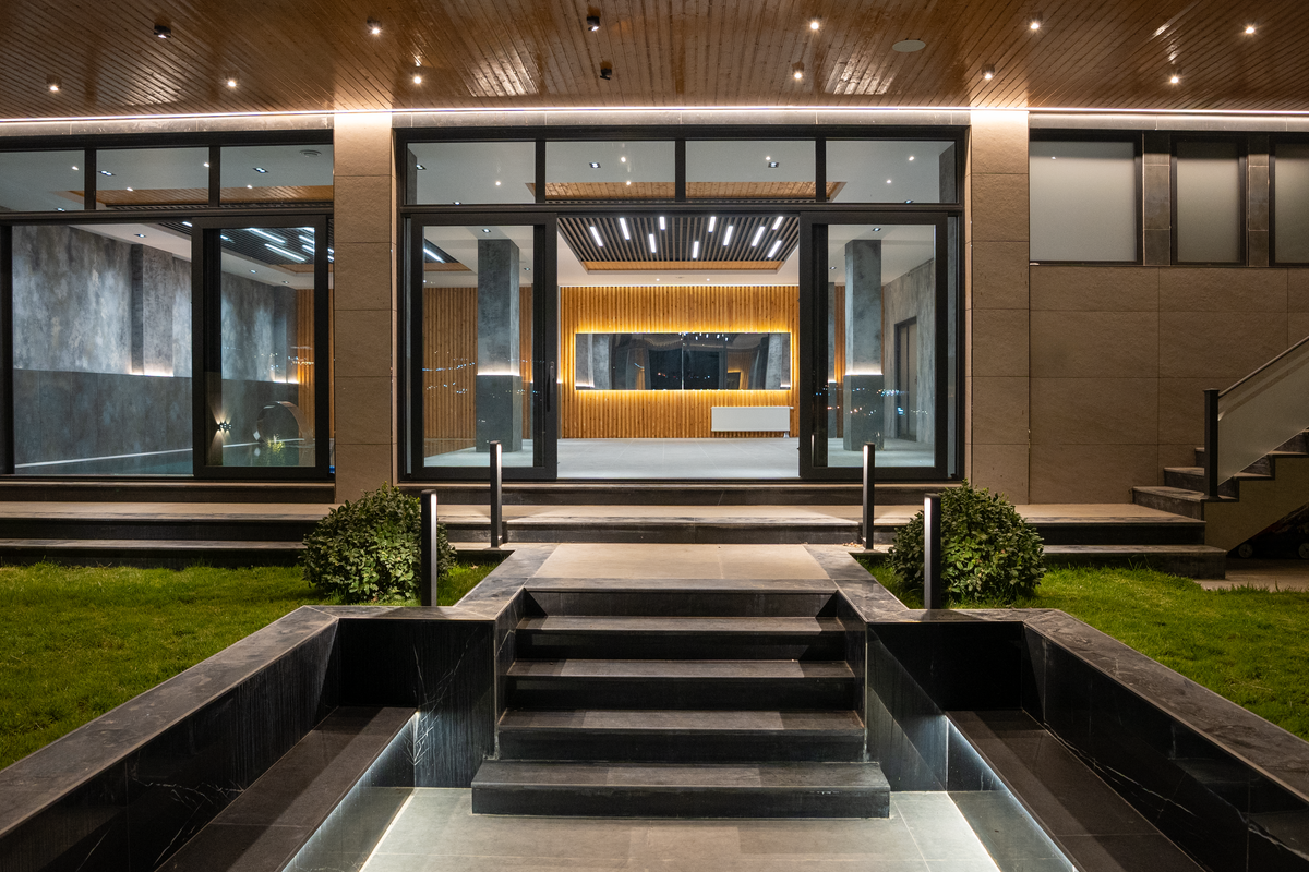 Elegant illuminated entrance to a modern luxury house at night with landscaped garden