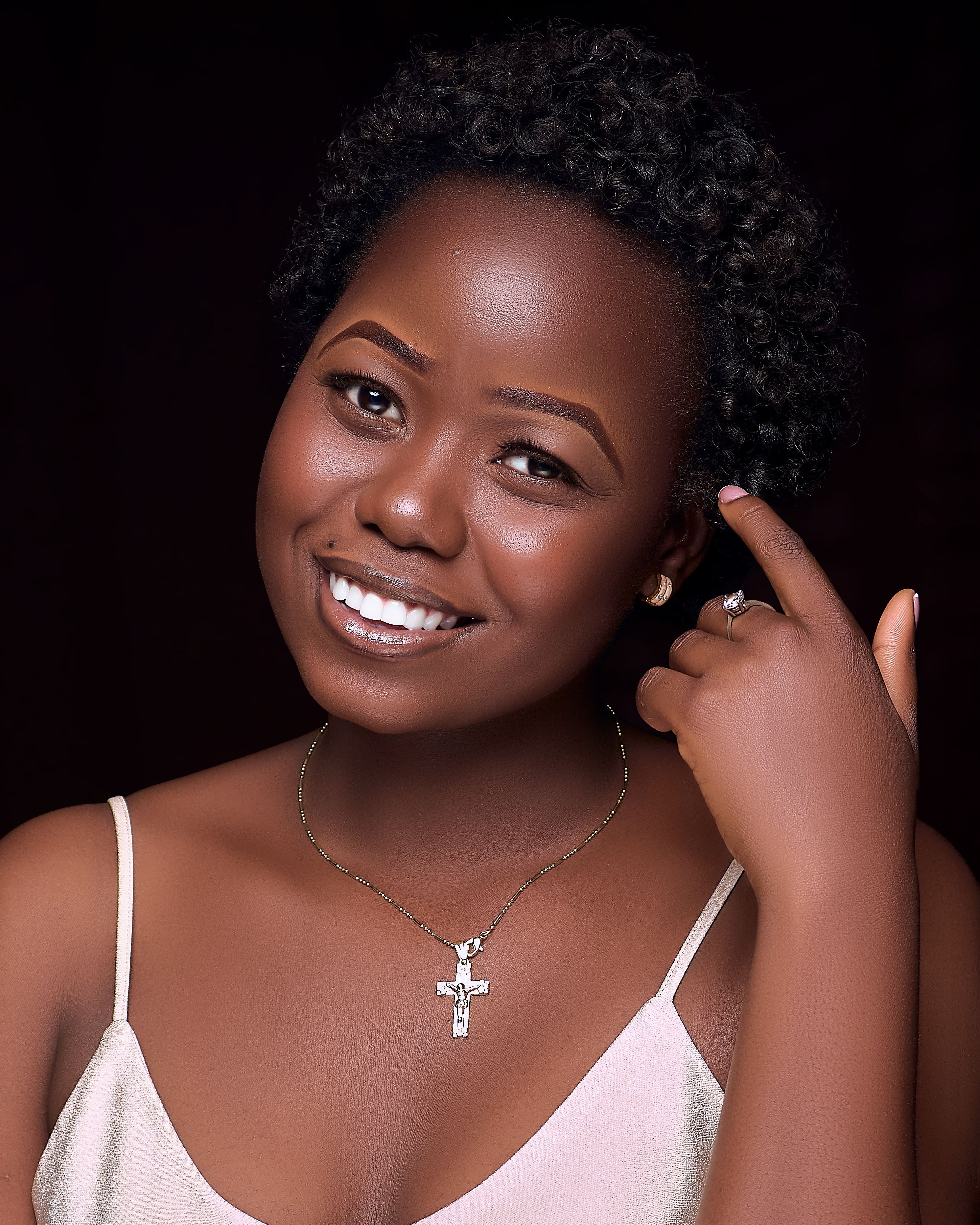 Charming studio portrait of a woman wearing a necklace, smiling against a dark background.