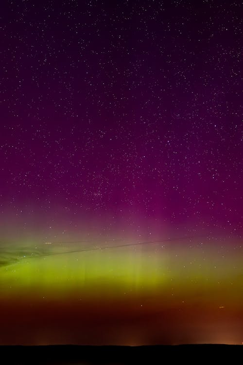 The aurora bore is seen in the sky over a purple and green sky