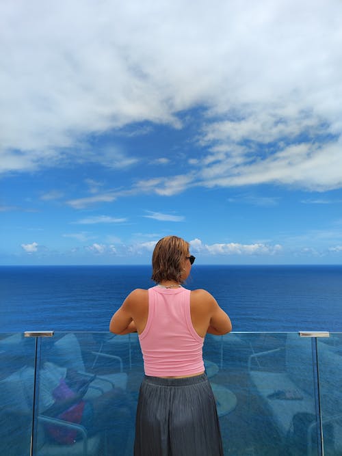 A woman standing on a balcony looking out at the ocean