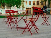 Red bistro chairs and tables in a Bratislava plaza, ideal for summer gatherings.