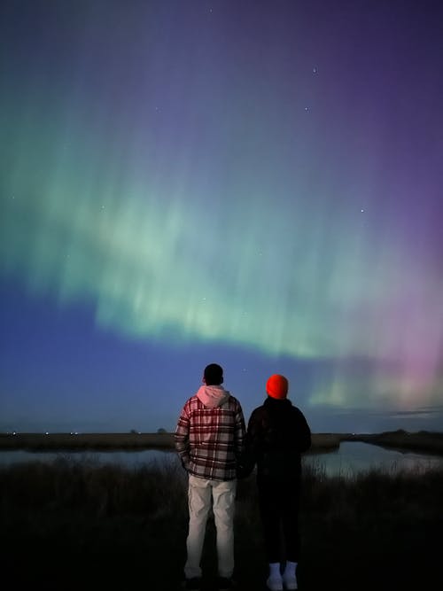 Two people standing in front of the aurora bore
