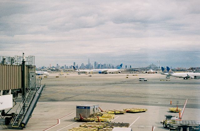 Aircraft waiting on JFK airport apron with New York City skyline in the background. — arriving in New York