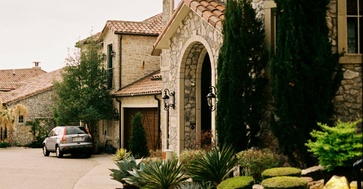 Elegant stone mansion with greenery and gated entry in Dallas, Texas.