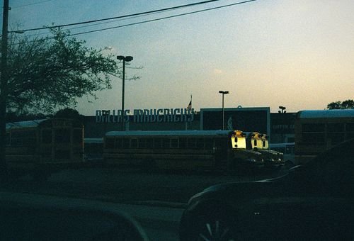Free School buses parked near the Dallas Mavericks Arena at dusk, a serene urban scene. Stock Photo
