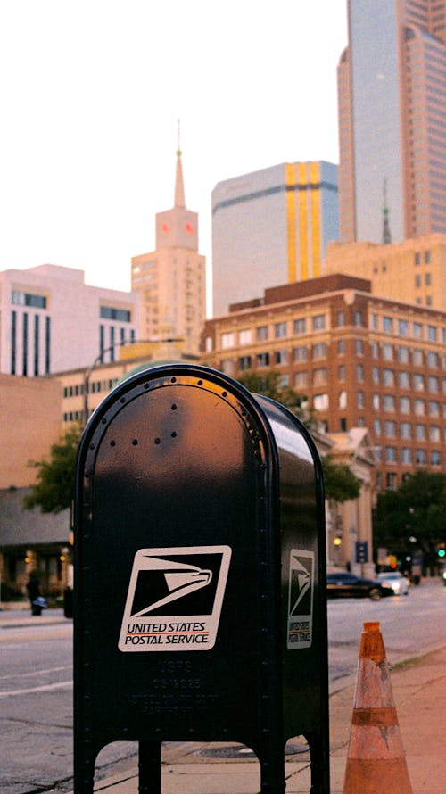 A mail box on a street corner with a city in the background