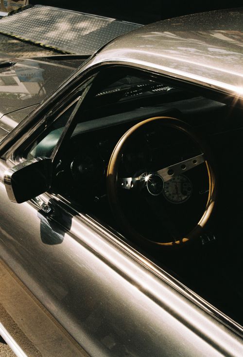 Free Side view of a vintage silver car with a brown steering wheel, captured in Berlin. Stock Photo