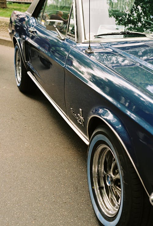 A blue classic car parked on the side of the road