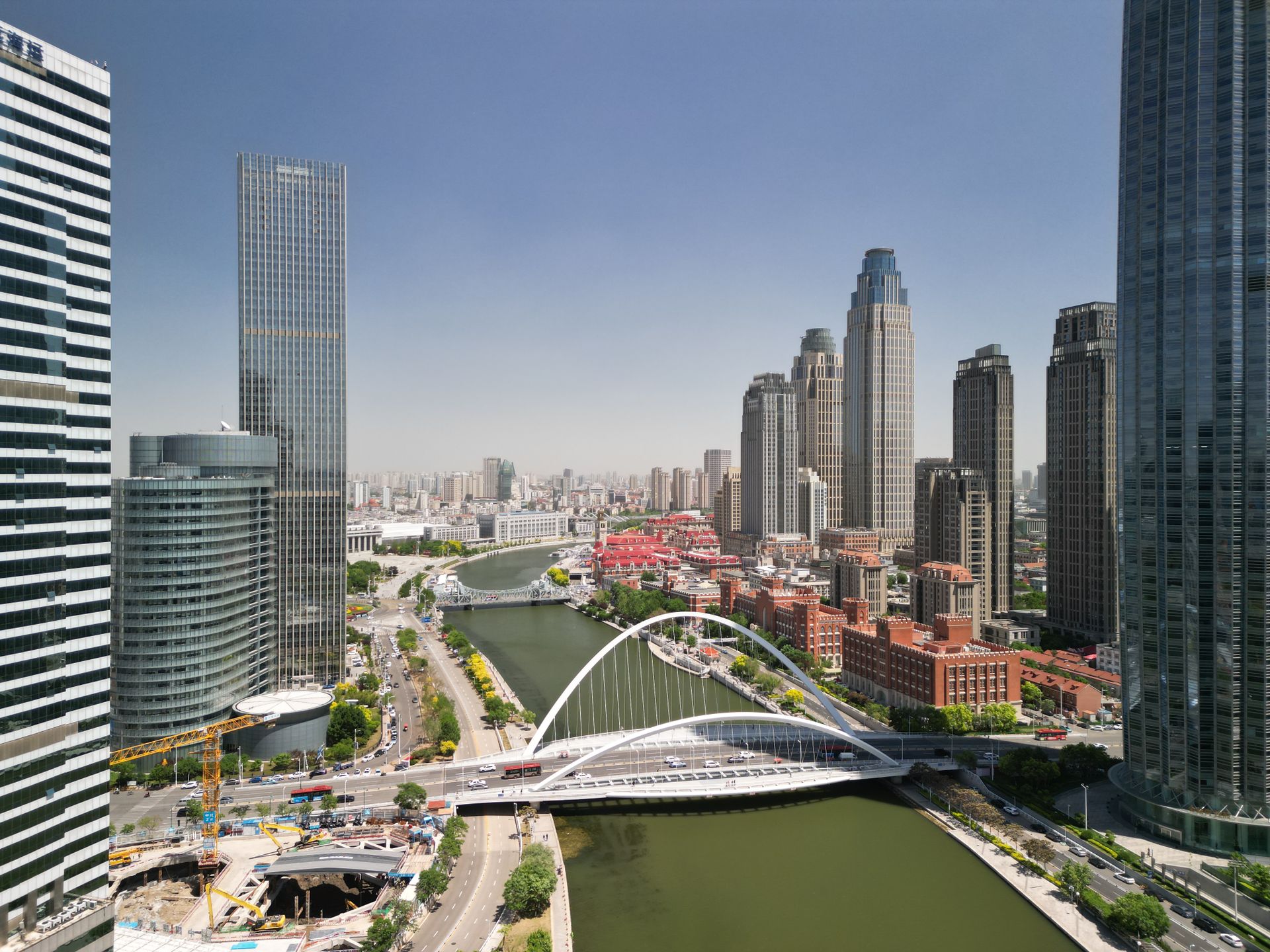 Aerial view of Tianjin city skyline featuring modern skyscrapers and distinctive bridge.