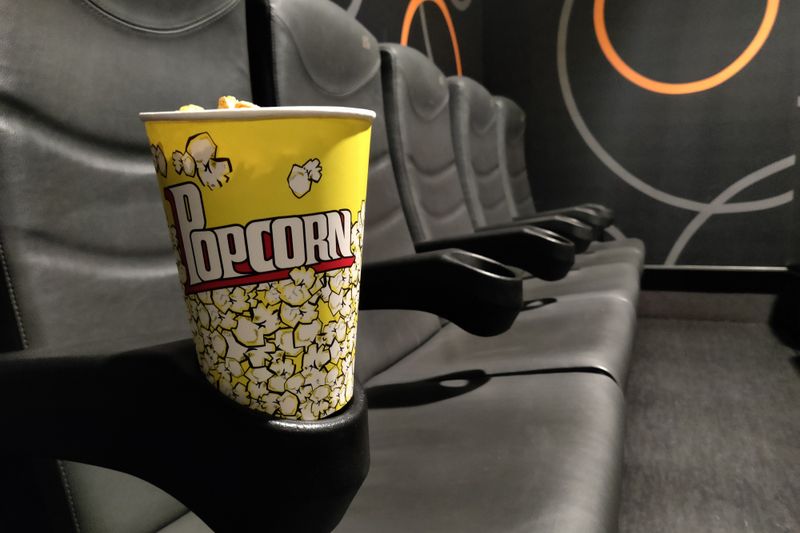 Yellow popcorn cup on a theatre armrest, capturing the essence of leisure in a cinema setting.
