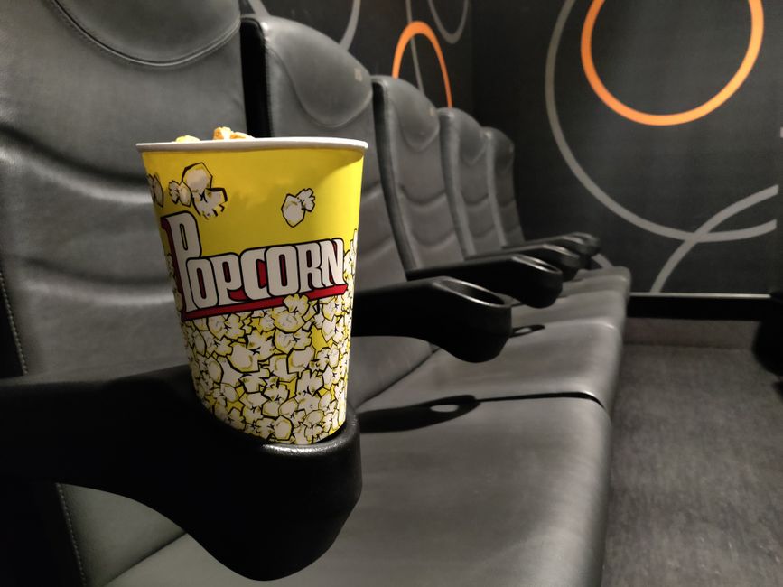 Yellow popcorn cup on a theatre armrest, capturing the essence of leisure in a cinema setting.