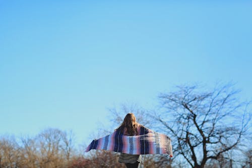 Woman Spreading Scarf Under Blue Sky