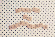 在圆点背景上，拼字游戏牌拼出了“让我们去冒险吧”