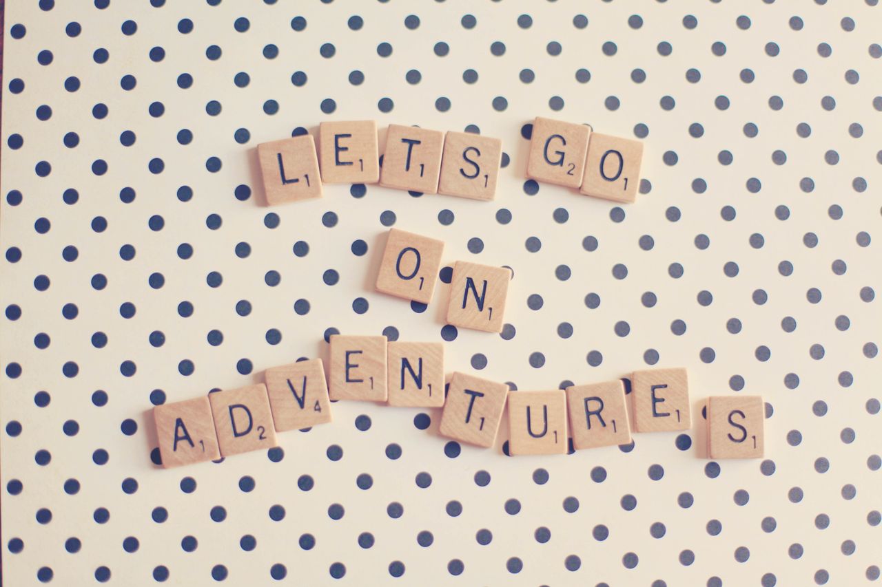 scrabble tiles spell let s go on adventures on a polka dot background