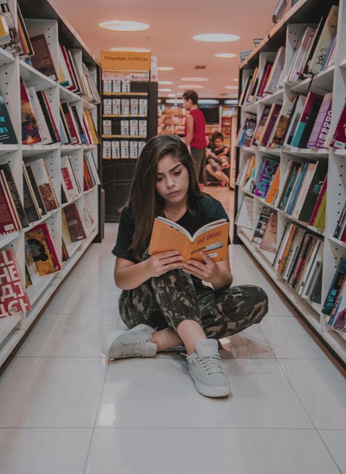 Vrouw Zittend Op De Vloer Tijdens Het Lezen