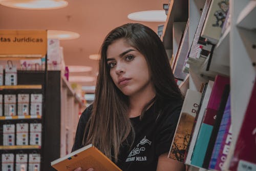 Femme En Haut Noir Se Penchant Par Bibliothèque