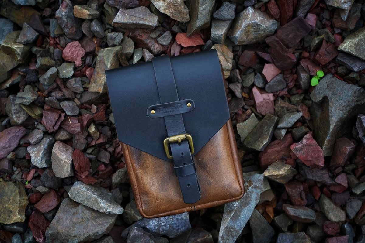 Navy and tan leather bag on a bed of stones