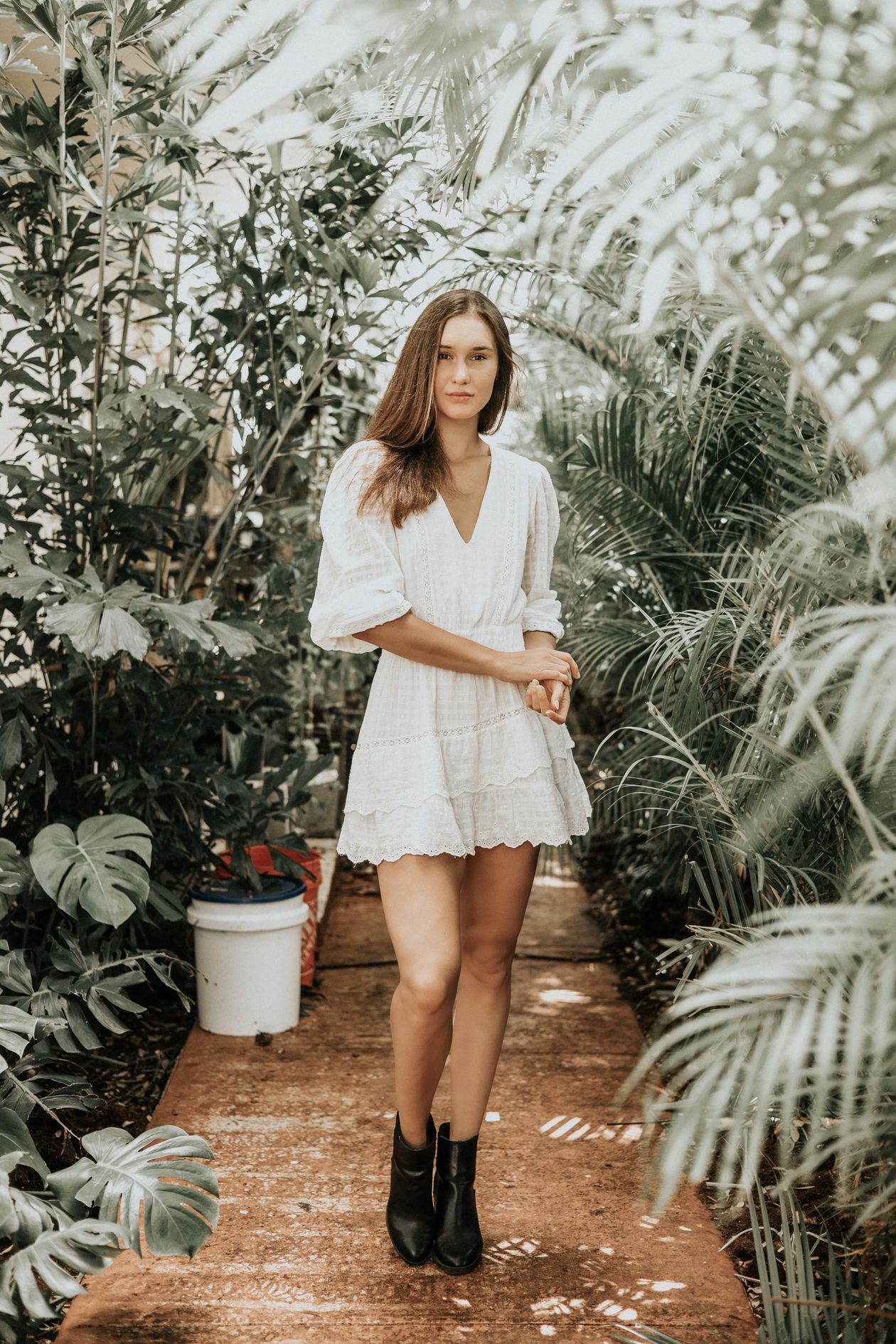Woman in a short white eyelet dress with puff sleeves standing on a garden path