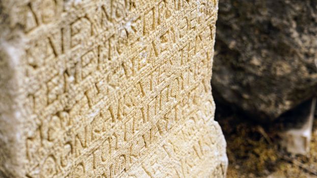 Close-up view of an ancient stone tablet with intricate engraved text, capturing historical artistry.