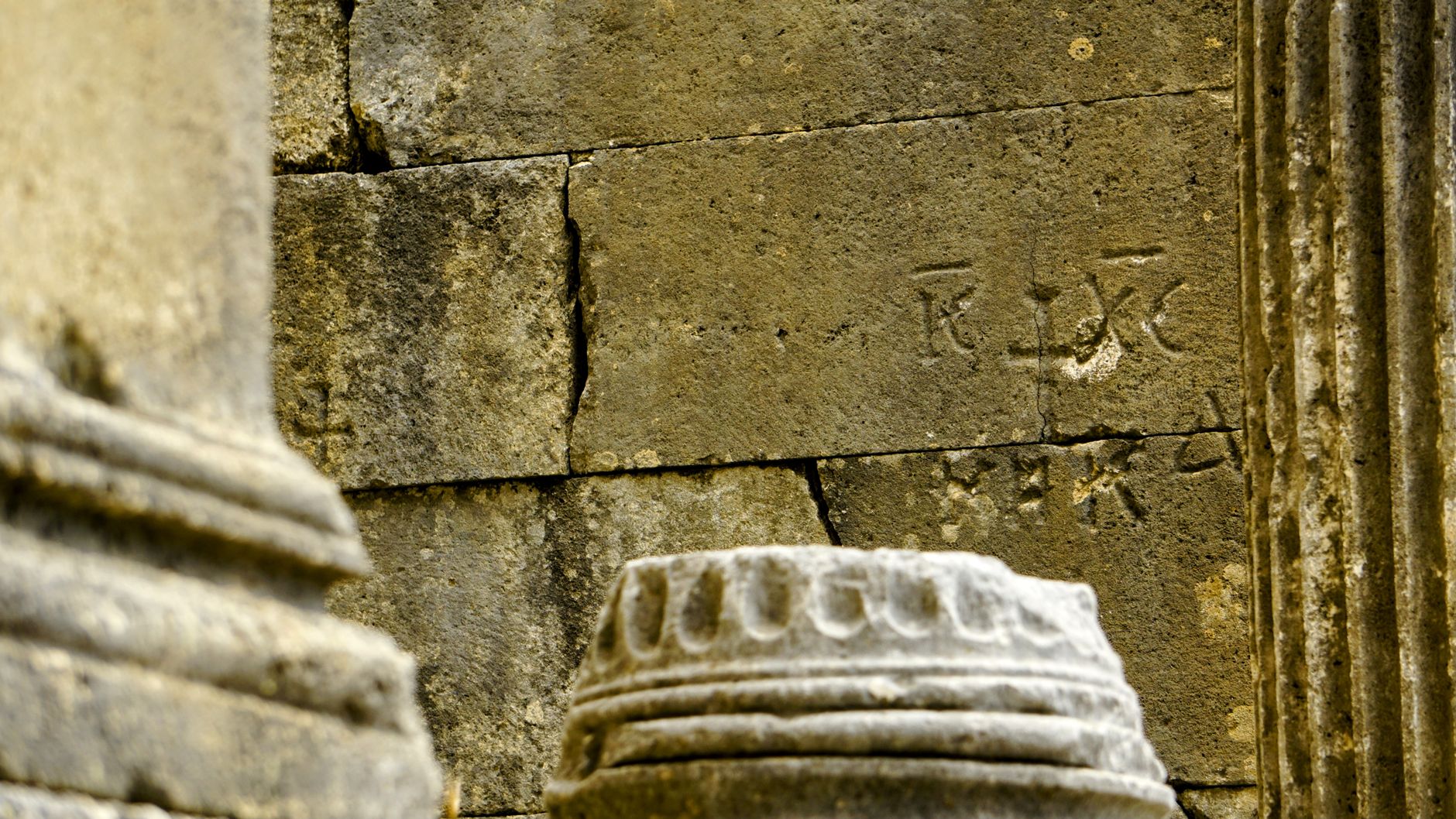 Close-up of ancient ruins with stone columns and weathered inscriptions.