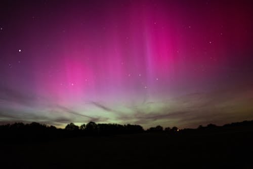 The aurora bore is seen in the sky over a field