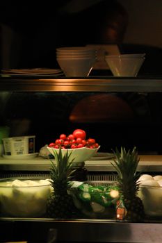 A vibrant display of tomatoes and pineapples on a kitchen shelf.