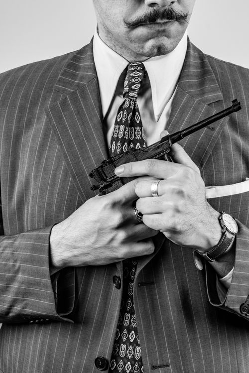 Free Black and white portrait of a man in a pinstripe suit holding a toy gun, conveying a vintage gangster vibe. Stock Photo
