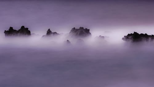 A long exposure photograph of rocks in the ocean